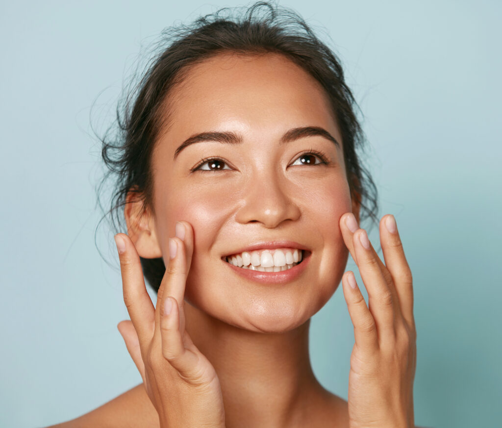 Smiling woman touching her healthy, glowing facial skin